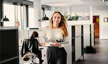 woman walking through office space with laptop