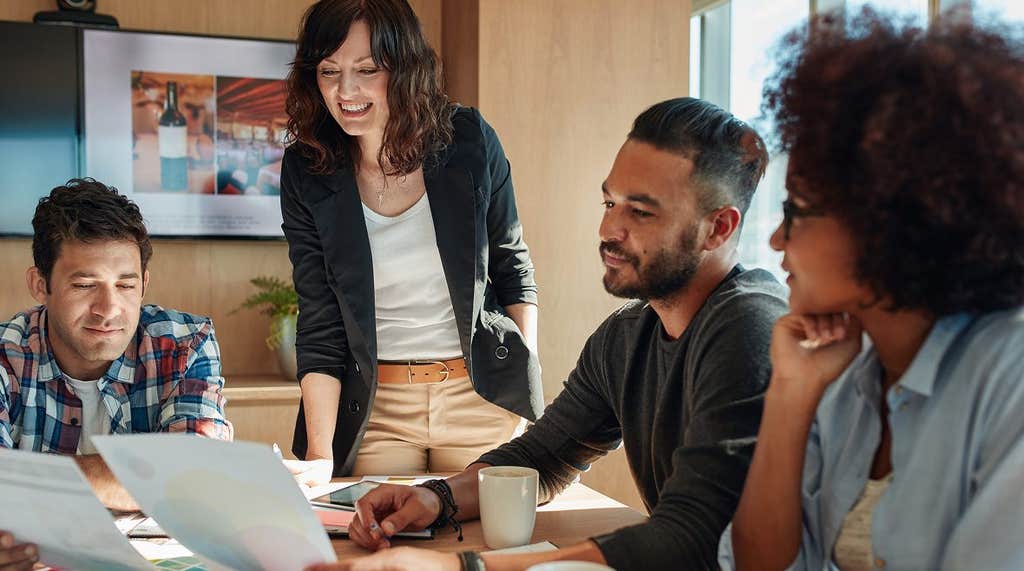 A diverse team collaborating around a table in a bright office, reviewing printed documents together