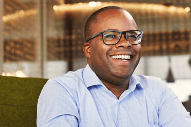 African-Amercian man in a blue shirt smiling towards the camera