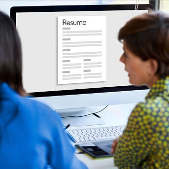 Two women looking at computer with a resume on the screen