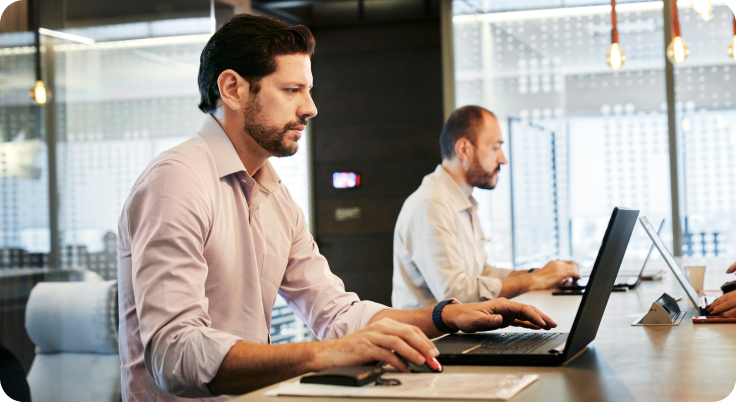 Focused professionals working on laptops in office