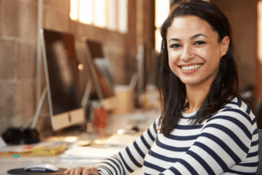 Woman in an office environment smiling towards the camera