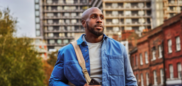 Man walking on the street with work bag on his shoulder.