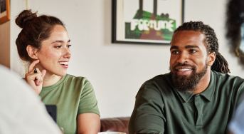 Two people sit next to each other smiling