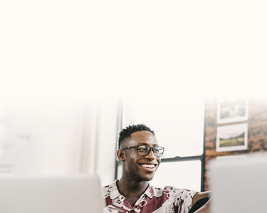 A smiling man working from a laptop at a desk