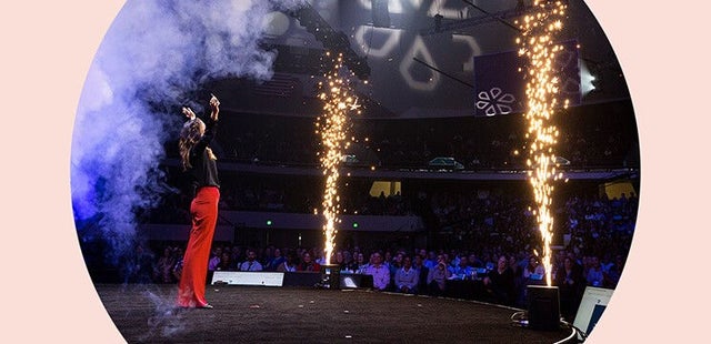 An individual standing on stage with pyrotechnics