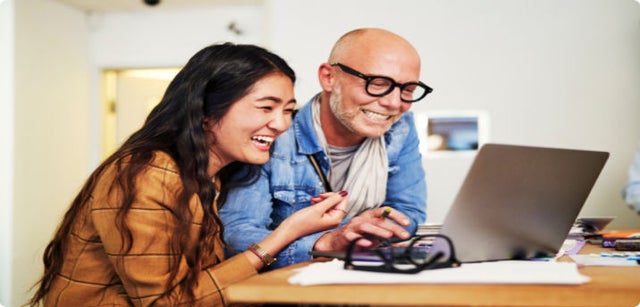 Photo of two people working on a laptop