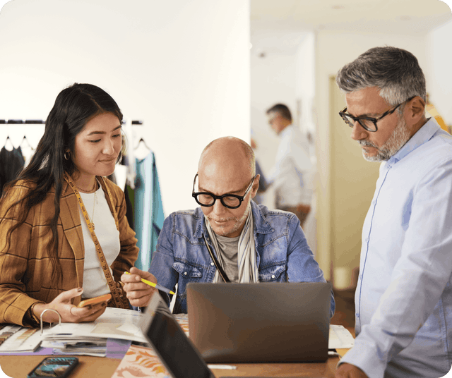 Creative team collaborating around office laptop