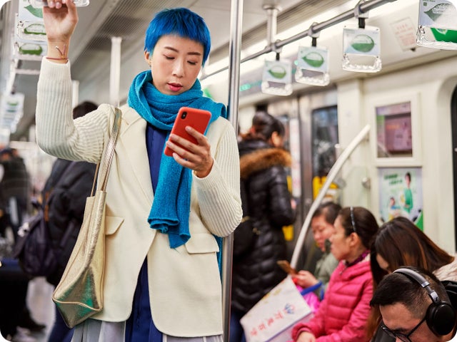 An individual standing inside of a train and holding onto the rails.