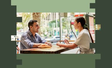 Two people sit at a table for an interview, having a conversation