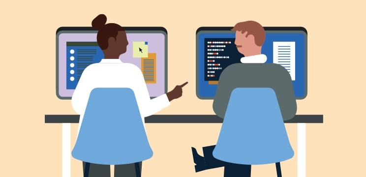 Two colleagues chat in front of their computer screens