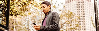 Man looking at his phone while standing in a park
