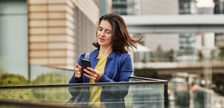 A person stands outside reading something on their phone.