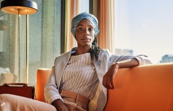 A photograph of someone sitting on a couch and looking directly at the camera.
