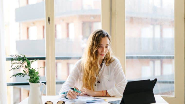 A professional writing notes at a desk by a window