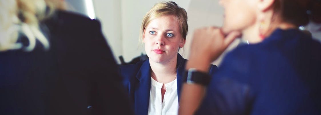 A sales manager listens to two salespeople