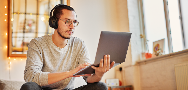 Man wearing headphones working on his laptop at home.
