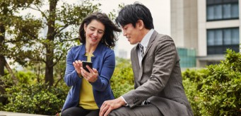 Zwei Personen, die im Freien gemeinsam auf ein Smartphone schauen.