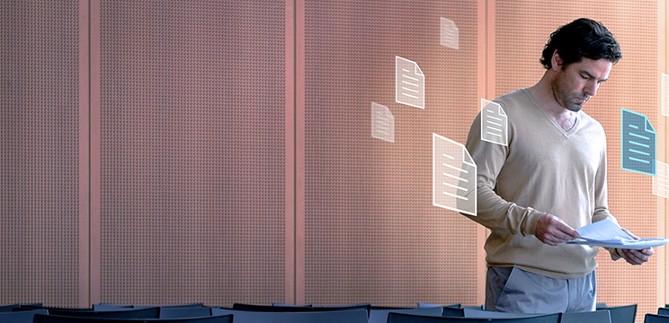 A man standing up looking down at a piece of paper in his hands