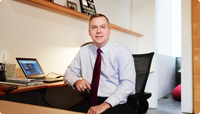 A male business professional in a tie sitting at a desk