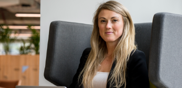 Business woman sits confidently smiling in a large chair