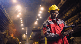 Man with hard hat, high-viz vest, and clipboard in dark tunnel