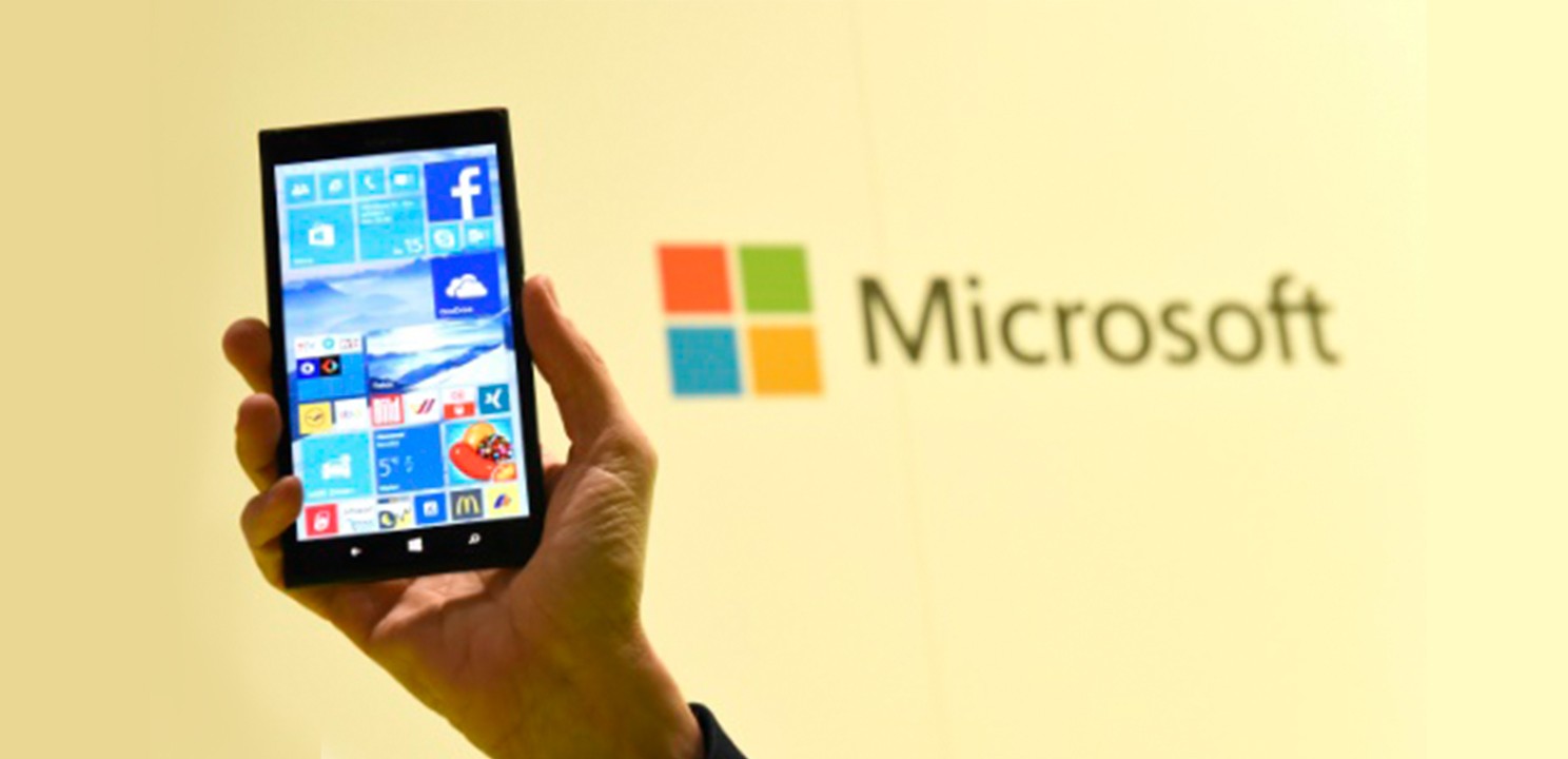 An android mobile device is held up in front of the Microsoft logo