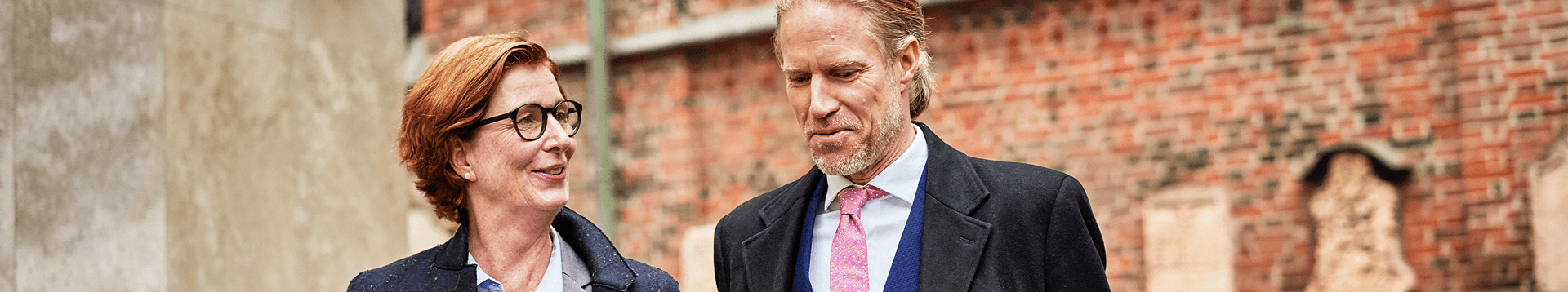 Man and woman walking outside a brick building deep in conversation