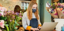 Image of a woman wearing a mask at her computer in a flower shop