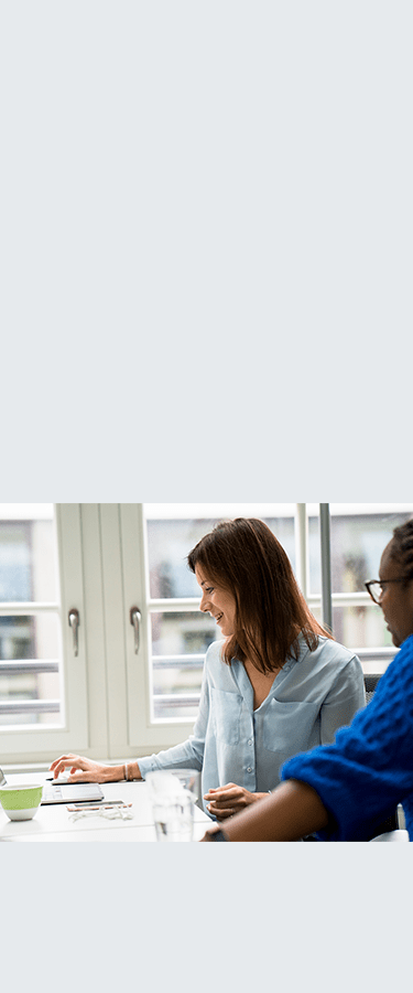 2 professional women looking at the screen of a laptop