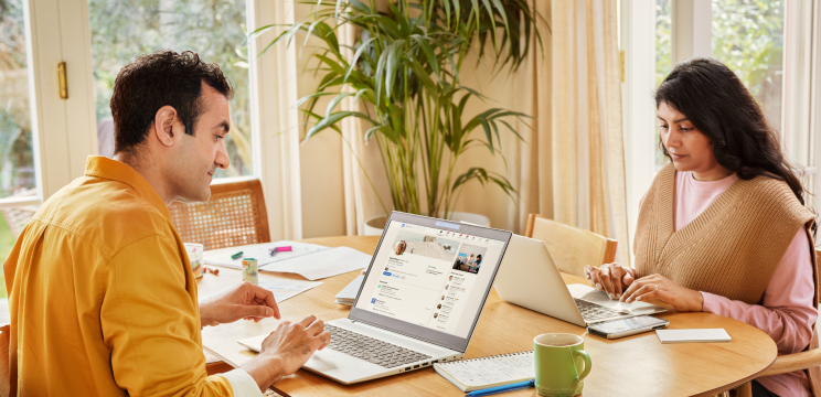 A photo of two people sitting at a table, working at their computers.