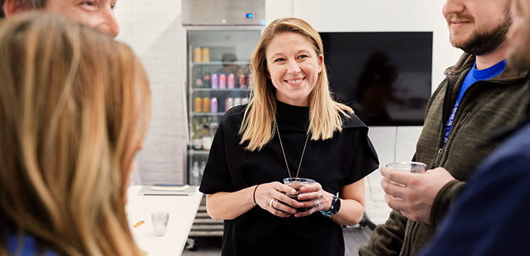 A satisfied employee smiles while talking with her coworkers.