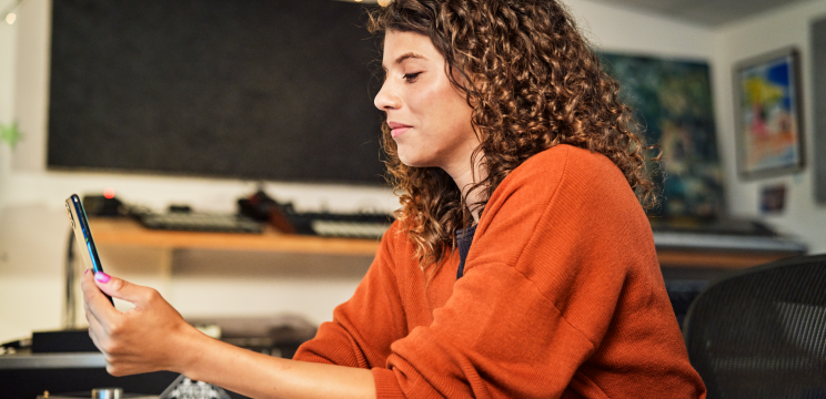 A woman sitting at a desk looking at her phone.
