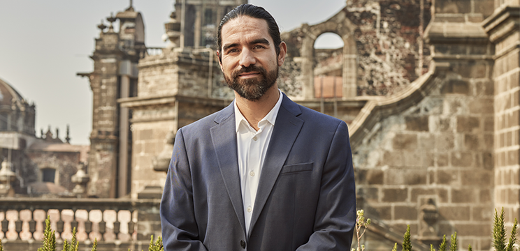 A professional wearing a suit stands outside and looks at the camera.